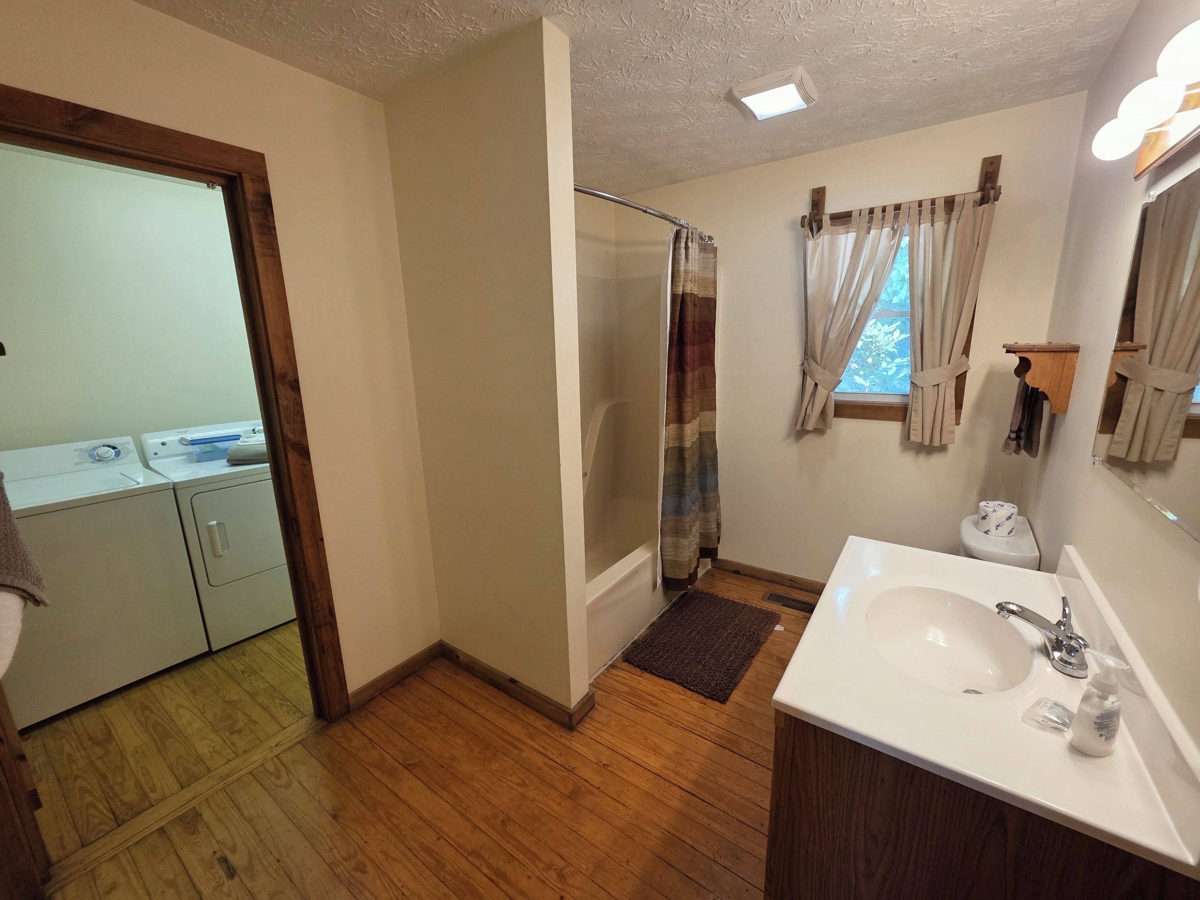 Un baño con ducha, inodoro, lavabo y suelo de madera.