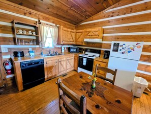 Cocina tipo cabaña con armarios de madera, estufa, microondas y refrigerador.