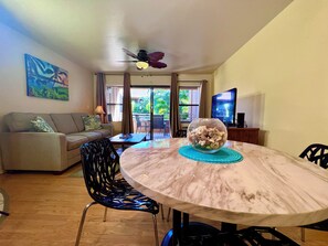 A living room with a round marble table, a sofa, a TV, and a ceiling fan.