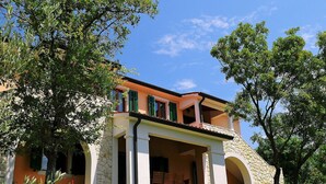 A two-story house with a stone facade, green shutters, and a covered porch with a chair. - Beautiful private villa for 10 guests with WIFI, pool, A/C, TV and terrace (Valhova)