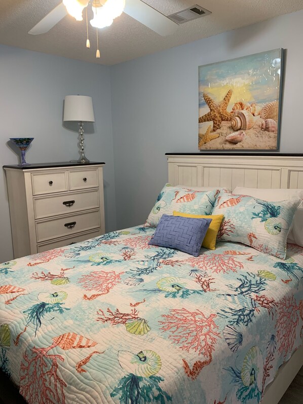 A bedroom with a bed, a nightstand, a lamp, and a wall painting. - Fort Morgan, on the Water, Fishing with Easy Gulf Access (Gulf Shores)