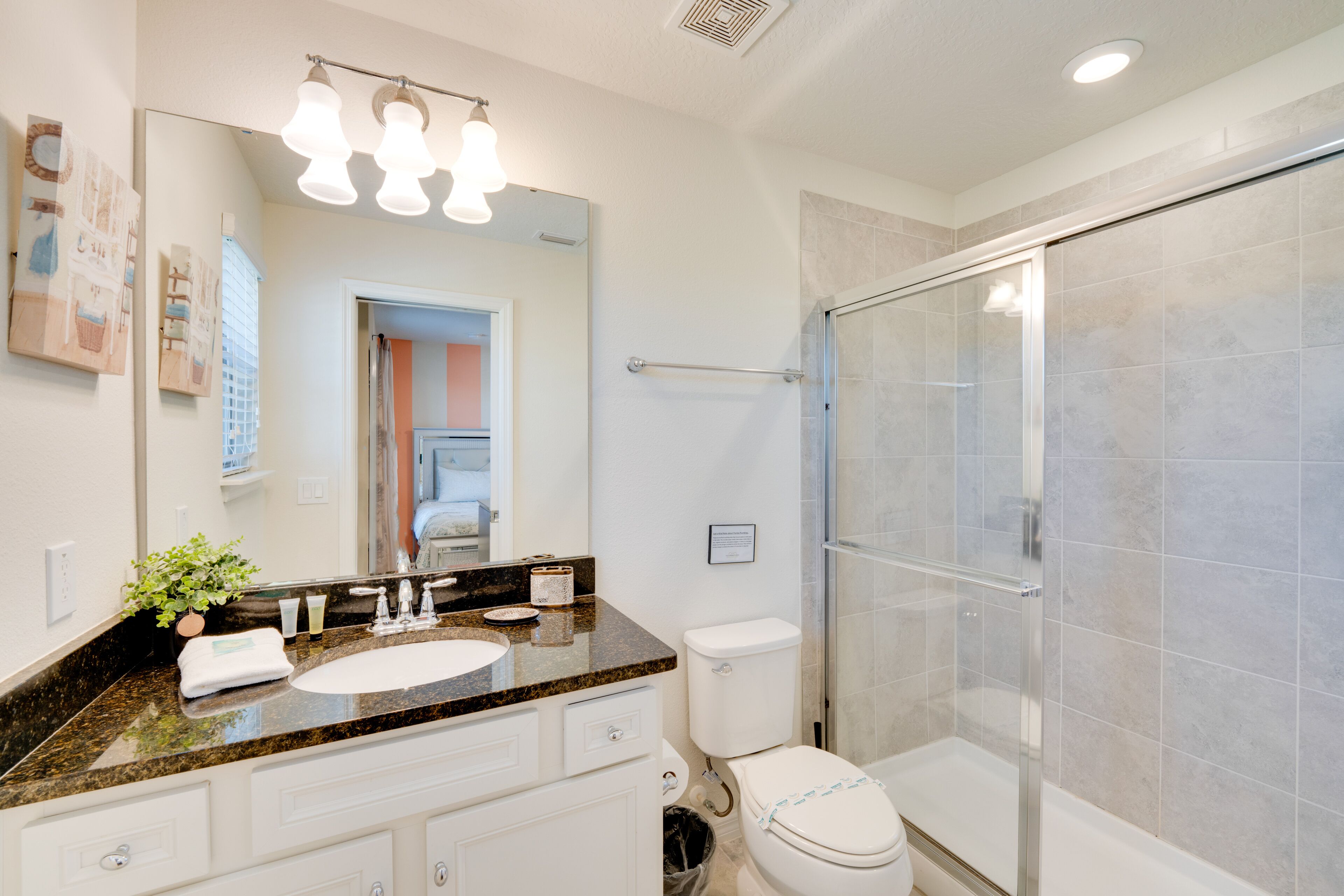 Un bagno moderno con un piano in granito, sanitari bianchi e cabina doccia in vetro.
