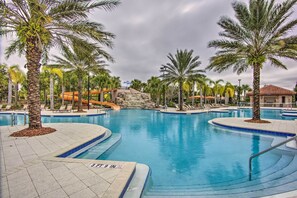 A large outdoor swimming pool surrounded by palm trees and lounge chairs. - Disney 7BR Villa w/ Pool, Spa & Lazy River! (Davenport)