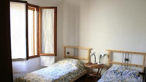 Une petite pièce simple, avec deux lits simples, une petite table et une chaise.