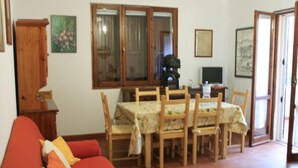 Un coin repas avec une table et des chaises, un meuble en bois et un canapé rouge.