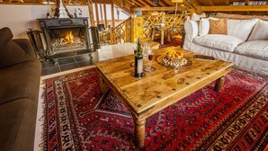 A cozy living room with a fireplace, wooden furniture, and a patterned rug.