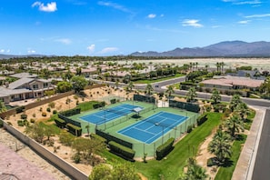 Un quartier résidentiel avec deux courts de tennis, entouré de maisons et de palmiers.