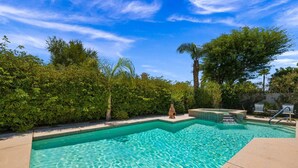 Une piscine à l’eau d’un bleu cristallin, entourée d’une végétation luxuriante et sous un ciel dégagé.