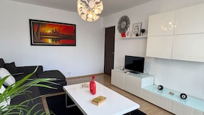 Una sala de estar moderna con un sofá blanco, una mesa de centro, un televisor y un cuadro en la pared.