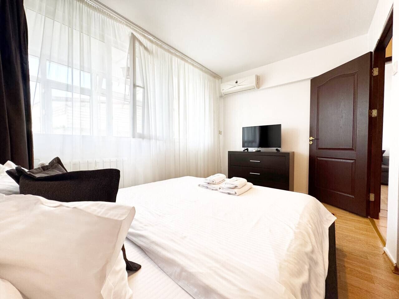 A hotel room with a bed, a TV, a dresser, and a door.