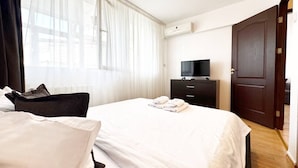 Una habitación de hotel con cama, televisión, cómoda y puerta.
