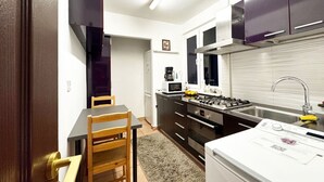 Una cocina compacta con comedor, refrigerador, microondas, estufa y pileta.