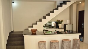 A modern kitchen with a curved island, wooden stools, and a staircase leading to another level. - 50meter from Seminyak beach,2BR Villa  (Seminyak)