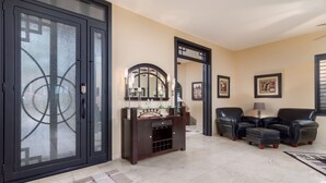 A spacious living area with a large sliding glass door, a dark wooden entertainment unit, and a seating area with leather sofas and a coffee table. - The Best Of Ahwatukee (Phoenix)