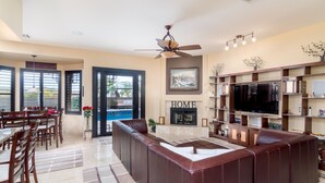 A spacious living area with a large brown leather sofa, a fireplace, a flat-screen TV, and a dining area with wooden chairs and a table. - The Best Of Ahwatukee (Phoenix)