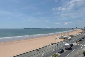 A coastal road with a beach on one side and a cityscape on the other.