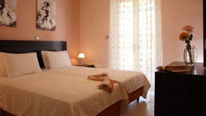 A neatly made bed with a white bedspread, a pair of slippers on the bed, and a vase with flowers on a nightstand. - VILLA PANTHEON, SYVOTA BAY, LEFKADA (SYVOTA LEFKADA)