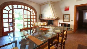 A dining area with a glass table, wooden chairs, and a brick fireplace. - Holiday Home for 5 People, Garden, 500m till Sea, A/C, WIFI, near Forte dei Marmi (Marina Dei Ronchi)