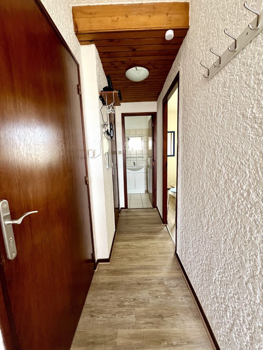 Un couloir doté d’un plancher en bois, d’une porte en bois et d’un mur à texture.