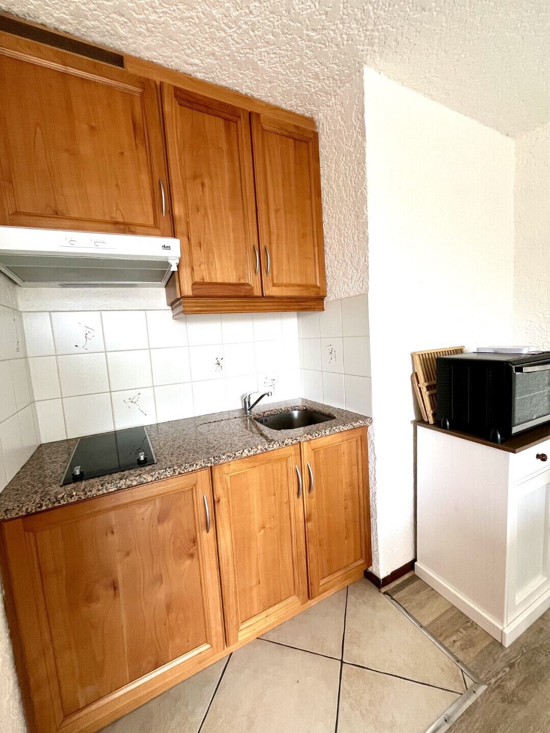 Une cuisine avec des meubles de rangement en bois, une cuisinière encastrée, un évier et un four à micro-ondes.