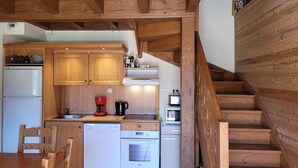 A kitchen with wooden cabinets, a dishwasher, an oven, a coffee maker, and a toaster. - Charming 2-bedroom half chalet with terrace, Pra Loup (Pra-Loup)