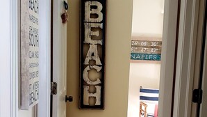 Un couloir avec un panneau en bois indiquant « PLAGE » et un autre panneau fixé au mur, sur lequel figure une liste de différentes plages.
