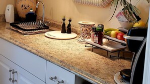 Une cuisine dotée d’un plan de travail en granit, de meubles blancs, d’un four à micro-ondes et d’un évier.