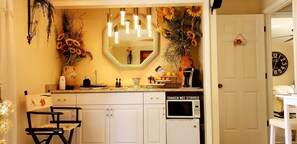 Kitchen area with central island, sink, and microwave, featuring a large mirror and decorative items.