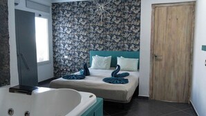 A bedroom with a large bathtub, a bed with blue and white bedding, and a floral wallpaper. - Villa Perla Blanca, 3 bed, free wifi, airco & heated pool (Playa Blanca)
