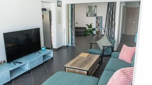 A modern living room with a flat-screen TV, a coffee table, and teal sofas. - Villa Perla Blanca, 3 bed, free wifi, airco & heated pool (Playa Blanca)