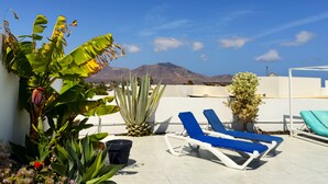 A rooftop terrace with lounge chairs, potted plants, and a view of mountains. - Villa Perla Blanca, 3 bed, free wifi, airco & heated pool (Playa Blanca)