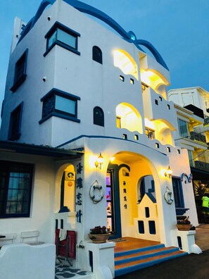 A modern building with a white facade, multiple balconies, and a staircase leading to the entrance. - Beach Love Homestay (Hengchun)