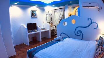 Un dormitorio con cama, escritorio, televisor y baño.