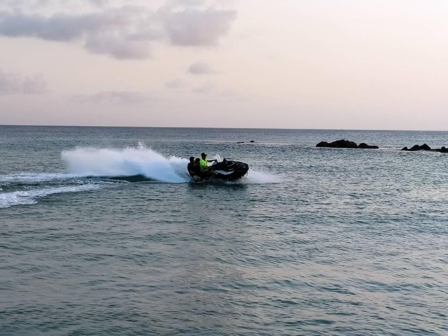 A jet ski on calm water with distant rocks and a clear sky.