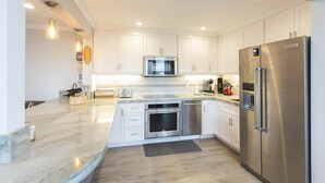 A modern kitchen with white cabinets, stainless steel appliances, and a marble countertop. - Across the street from the beach in Del Mar!  1757 Coast Blvd (Del Mar)