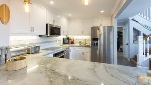 A modern kitchen with white cabinets, stainless steel appliances, and a marble countertop. - Across the street from the beach in Del Mar!  1757 Coast Blvd (Del Mar)
