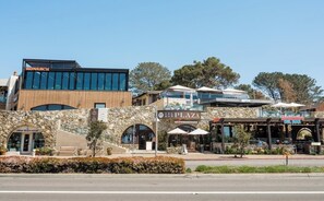 A commercial building with a stone facade, a modern glass structure, and various storefronts including a coffee shop and a restaurant.