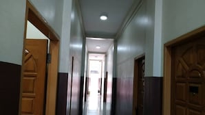 A hallway with wooden doors and a light-colored floor. - Grand Diamond Guest House (Mingaladon Township)