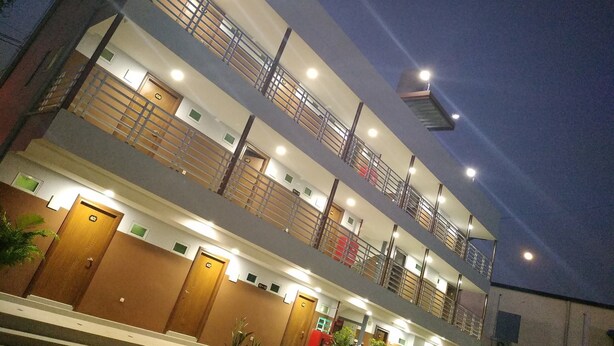A multi-story hotel with a modern design, featuring balconies on each floor, well-lit interiors, and a series of doors likely leading to guest rooms. - Grand Diamond Guest House (Mingaladon Township)