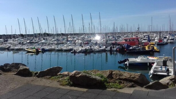 Ein Yachthafen mit zahlreichen angestaubten Booten, einem klaren Himmel und ruhigem Wasser.