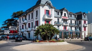 Ein mehrstöckiges Hotel mit Balkonen, einem zentralen Innenhof mit Palmen und blauem Himmel.