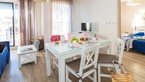 Ein modernes Hotelzimmer mit Essbereich, Fernseher und Bett mit blauem Kopfteil.