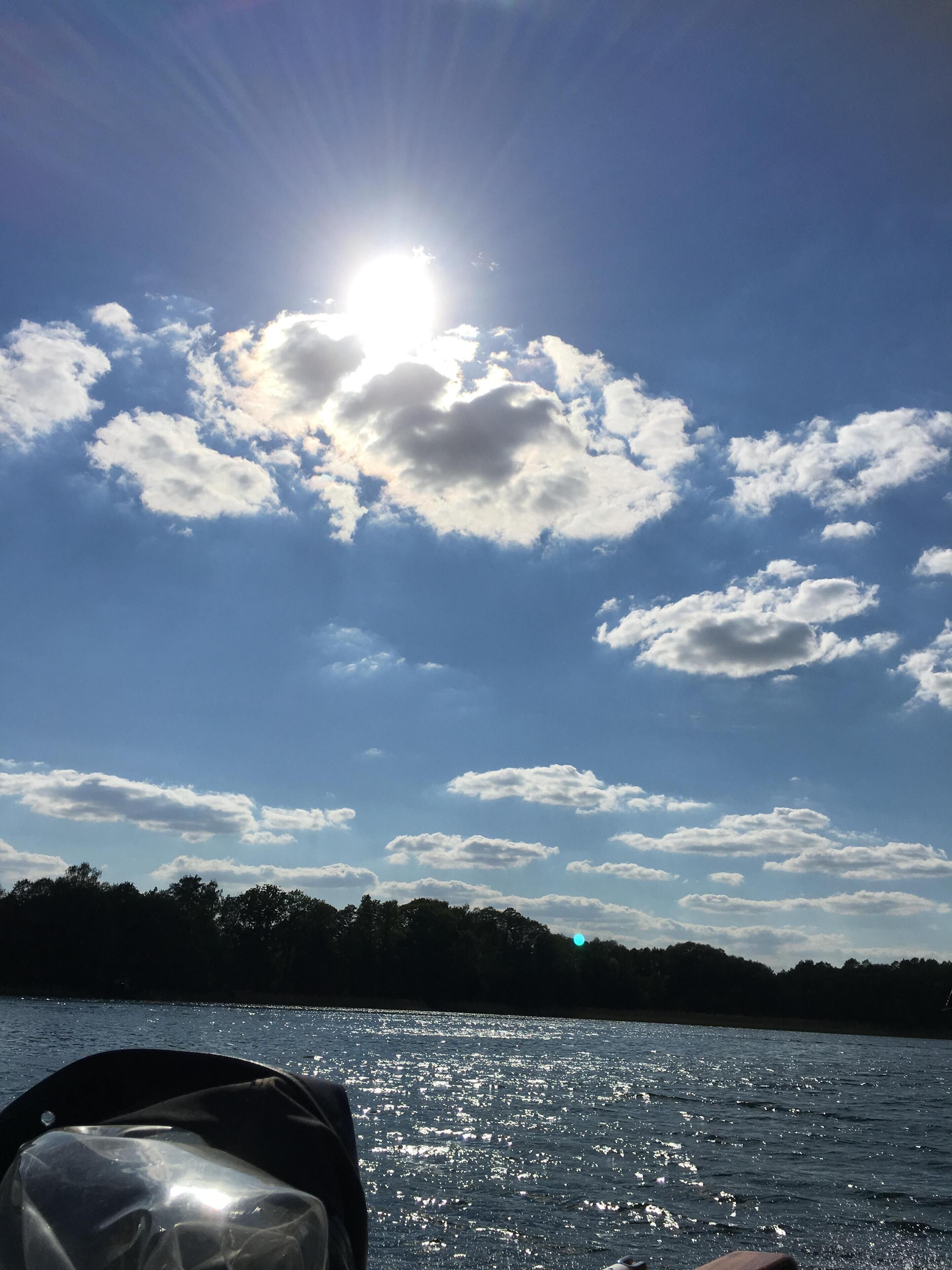 A clear sky with scattered clouds and a bright sun.
