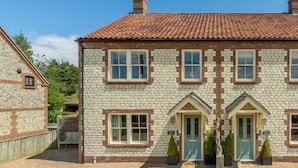 A stone building with a tiled roof, multiple windows, and a small porch area.