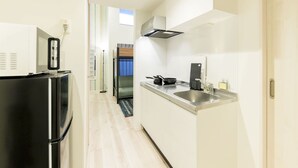 A compact kitchen with a refrigerator, sink, and stove. - Trip Pod Yoshizuka B (Fukuoka)