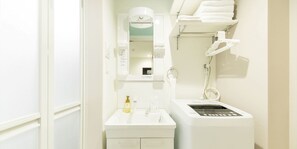 A bathroom with a white sink, a mirror, a hairdryer, and a towel rack. - Trip Pod Yoshizuka B (Fukuoka)
