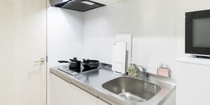 A compact kitchen with a built-in stove, a sink, and a refrigerator. - Trip Pod Yoshizuka B (Fukuoka)