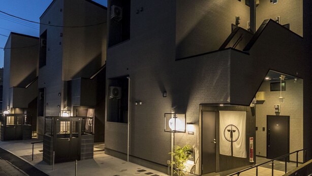 Un bâtiment moderne avec un escalier, une porte sur laquelle est accrochée une serviette et un panneau orné d’un symbole circulaire.