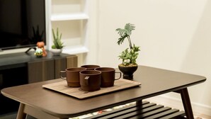 Une petite table en bois sur laquelle se trouve un plateau contenant plusieurs tasses brunes et une plante en pot.