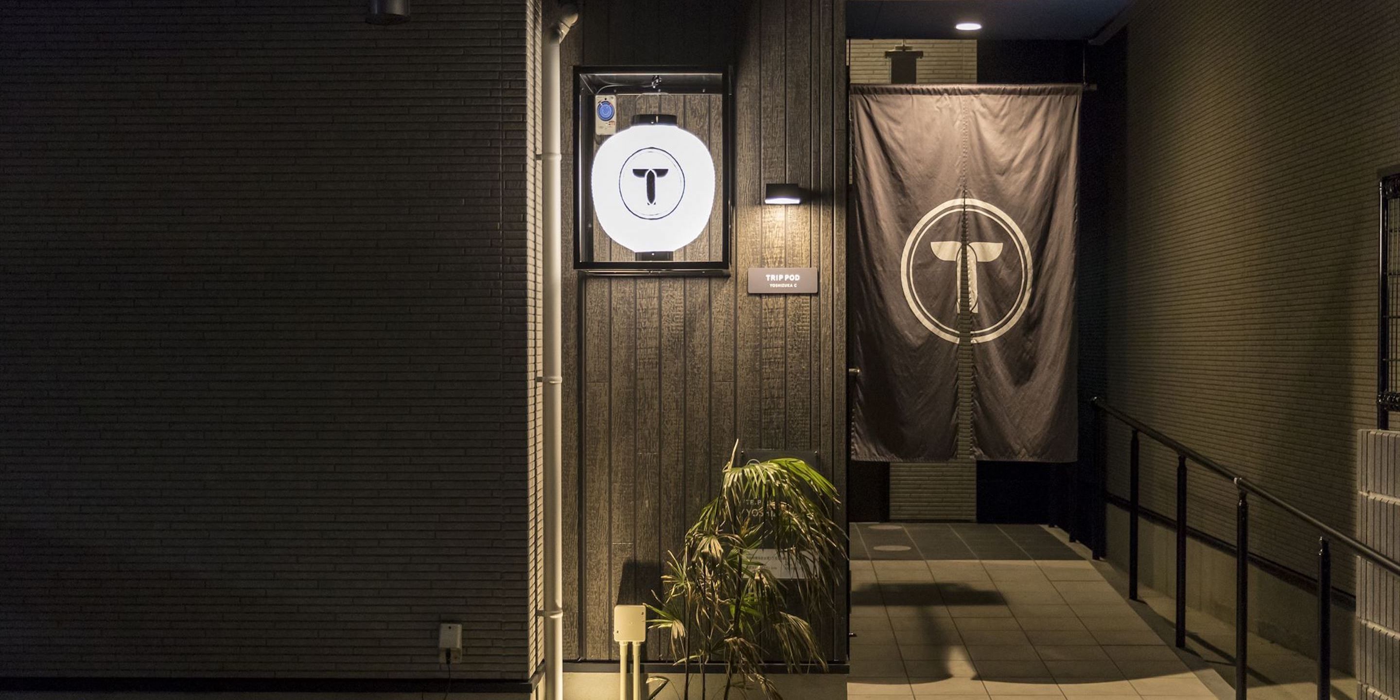 A hallway with a sign indicating a TRIP POD and a large T-shaped logo on a curtain.